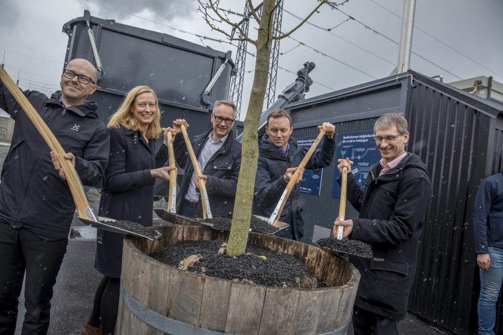 Jonas Eliasson, Head of Traffic Department, City of Stockholm, Katarina Luhr, Vice Mayor of Environment, City of Stockholm in Stockholm, Krister Schultz, CEO, Stockholm Water, James Anderson, Government Innovation, Bloomberg Philanthropies, and Anders Egelrud, CEO, Fortum Värme shovels biochar from a wheelbarrow to add to a newly planted tree. Credit: Casper Hedberg
