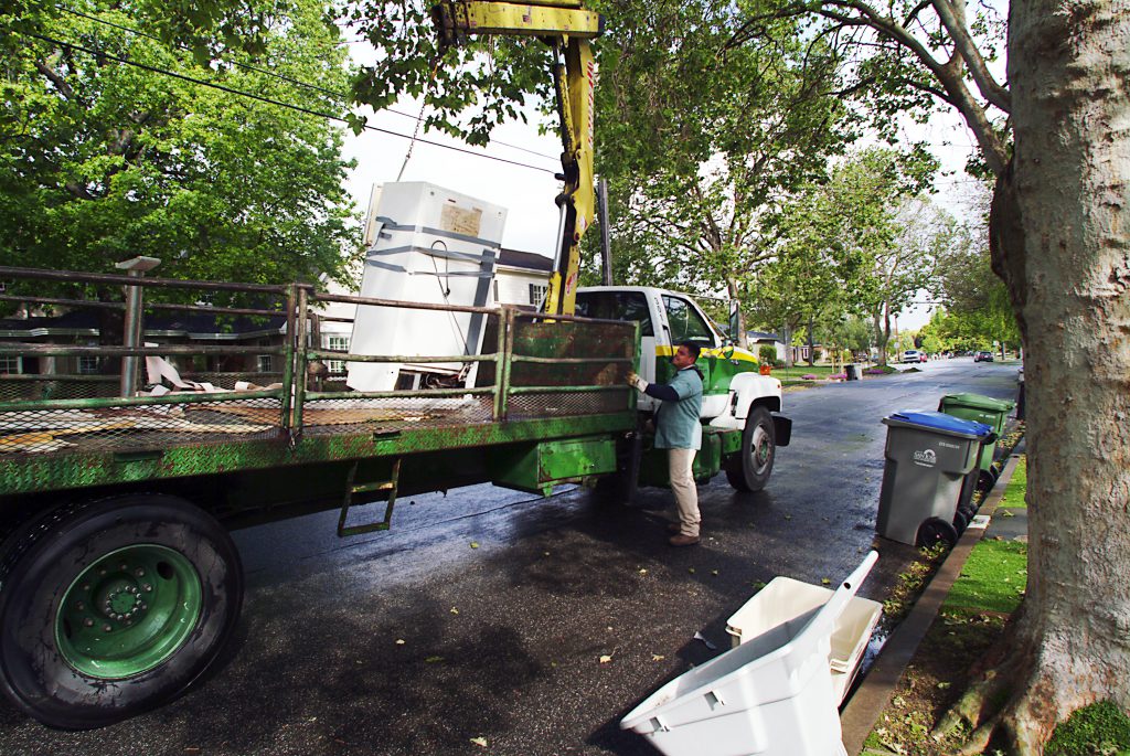 A city worker loads a refrigerator onto a large truck through San Jose's Large Item Collection program